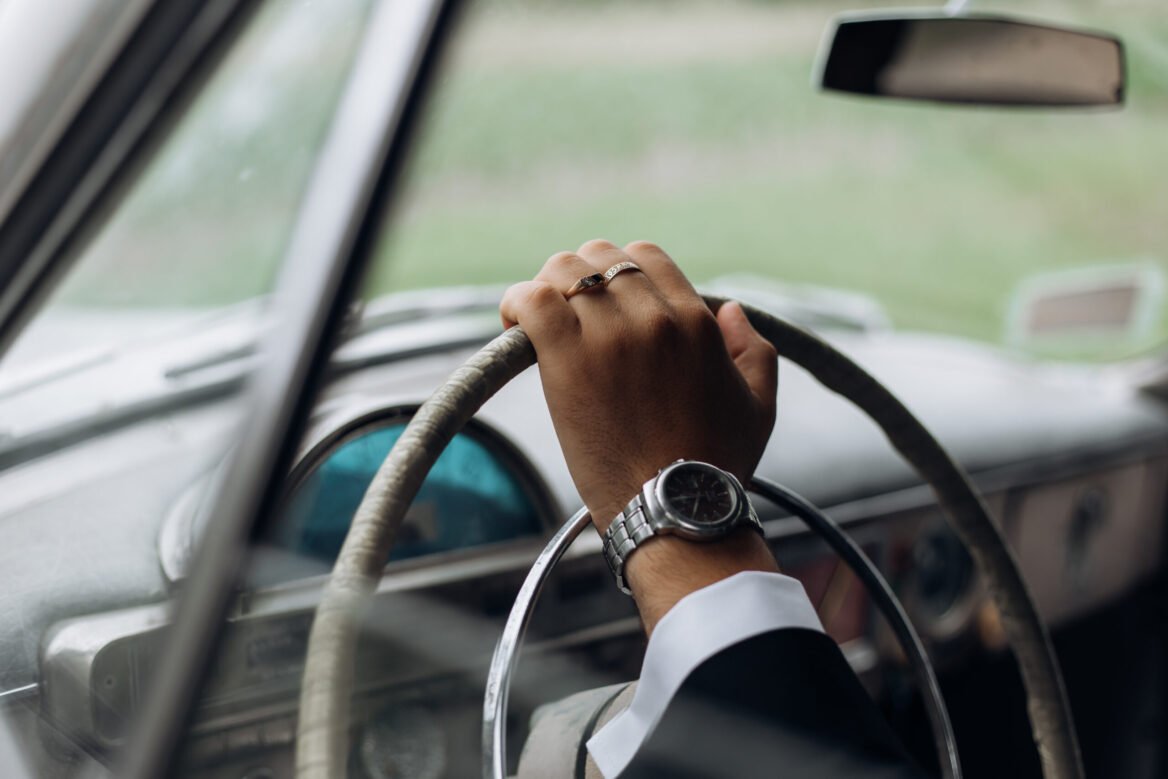 Hand of a man on the steering wheel of an old fashioned car, man's watch